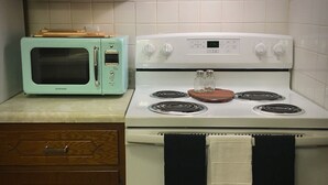 Una cocina con un horno de estilo vintage, una estufa de cuatro quemadores y un armario de madera.