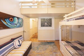 Una habitación con literas, un cuadro, una alfombra y una puerta que da a otra estancia.
