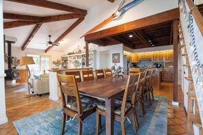 A spacious dining area with a wooden table and chairs, a kitchen with wooden cabinets, and a visible staircase.