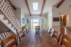 A dining area with a wooden table and chairs, a staircase with a lattice design, and a view through a glass door.