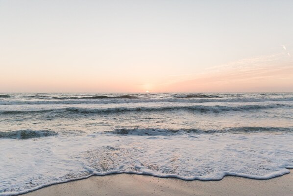 A beach with waves and a sunset.