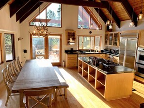 Enjoy cooking in this well-equipped kitchen with a large island, modern appliances, and a dining area with a long table.