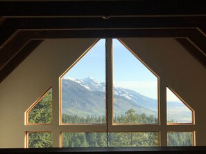 Panoramic views of snow-capped mountains and dense forest from a large window.