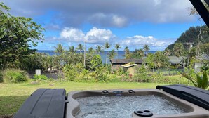 Een jacuzzi met uitzicht op een tropisch landschap en de oceaan.