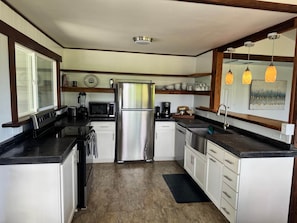 A compact kitchen with a refrigerator, microwave, stove, and coffee maker.