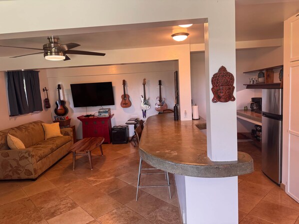 Una sala de estar con sofá, mesa de centro, televisor y guitarras colgadas en la pared.