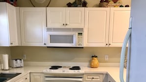 A kitchen with white cabinets, a microwave, an oven, a stove, a refrigerator, and a wooden floor. - Beautiful  2B/2B, ground floor condo in Riverwalk on Arrowhead Golf course ! (Myrtle Beach)