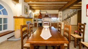 A dining area with a wooden table, chairs, and a central island with a sink and stove.