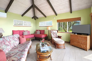 A living room with a sofa, armchair, and a glass coffee table.