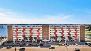 A hotel with a modern design, featuring a central courtyard with palm trees and a view of the water.