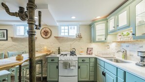 A kitchen with green cabinets, a white stove, and a rustic chimney.