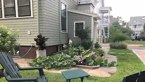 A residential property with a front yard, a small garden, and two outdoor seating areas.