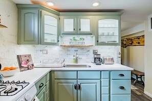 A kitchen with light blue cabinets, a white countertop, a stove, a coffee maker, and a toaster.