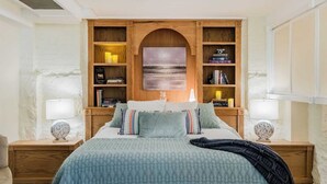 A bedroom with a bed, two nightstands, a wooden bookshelf, and a painting on the wall.