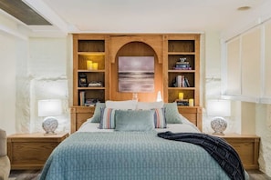 Una camera da letto con un letto, due comodini, una libreria in legno e un quadro appeso al muro.