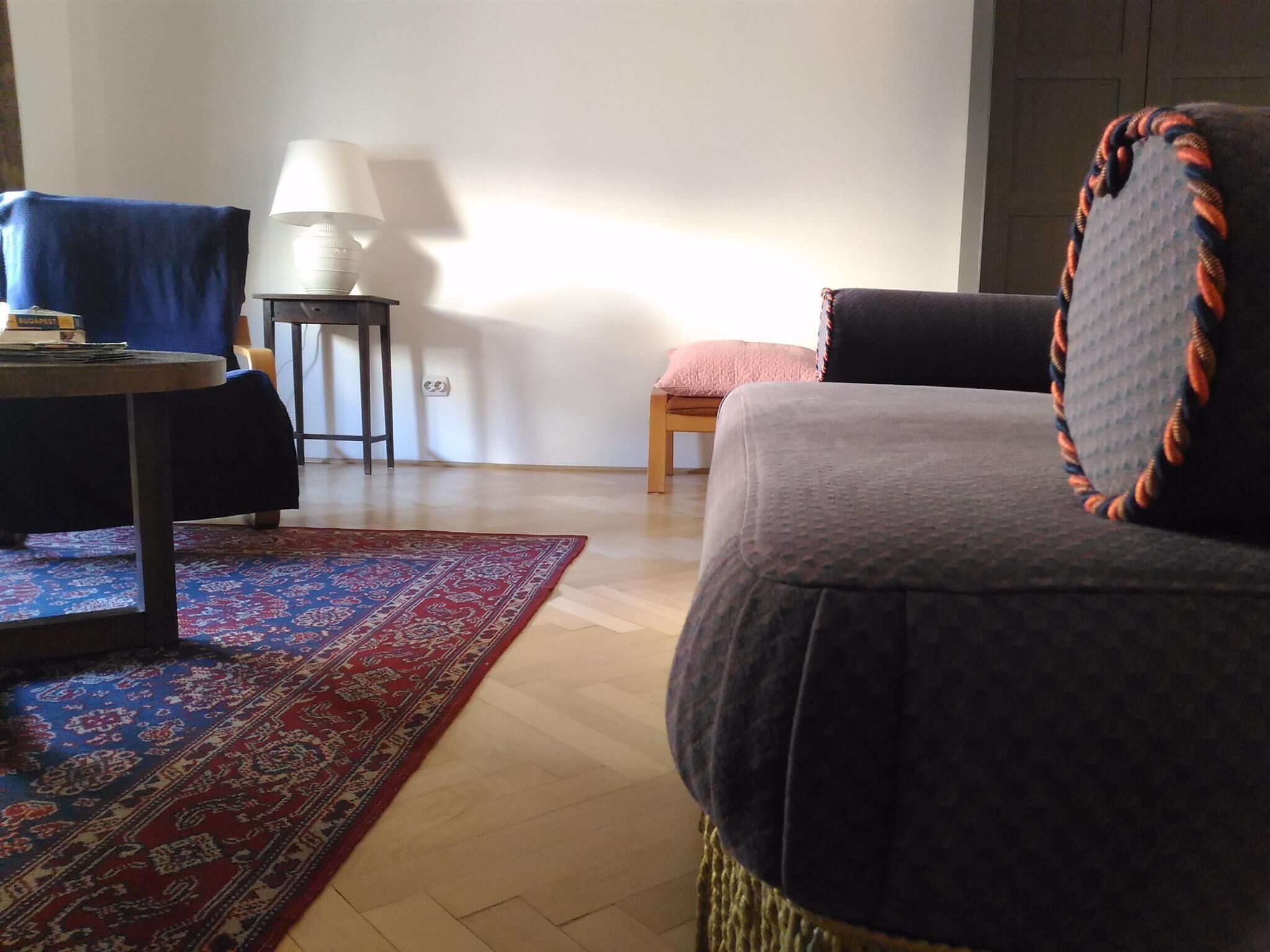 A living room with a sofa, a small table, a lamp, and a patterned rug.