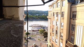 Vista desde un balcón sobre un río con barcos, un puente y edificios.