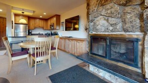 Una cocina moderna con armarios de madera, una chimenea de piedra y un comedor con mesa y sillas.