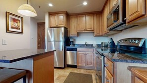 Cocina con gabinetes de madera, electrodomésticos de acero inoxidable y encimera de granito.