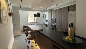 Eine moderne Küche mit einer zentralen Kochinsel, Barhocker, einem Spülbecken und einem Kühlschrank.