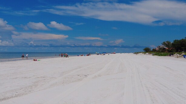 A wide sandy beach with a clear sky and a few people scattered along the shore. - Relax near St. Pete & Clearwater Beaches, stay in our 2-bedroom beach condo (Indian Rocks Beach)