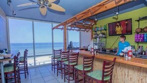 A bar area with a view of the ocean, wooden chairs, and a bartender. - Royal Beachfront Unit, Sleeps 6, Walk to Pier Park (Panama City Beach)