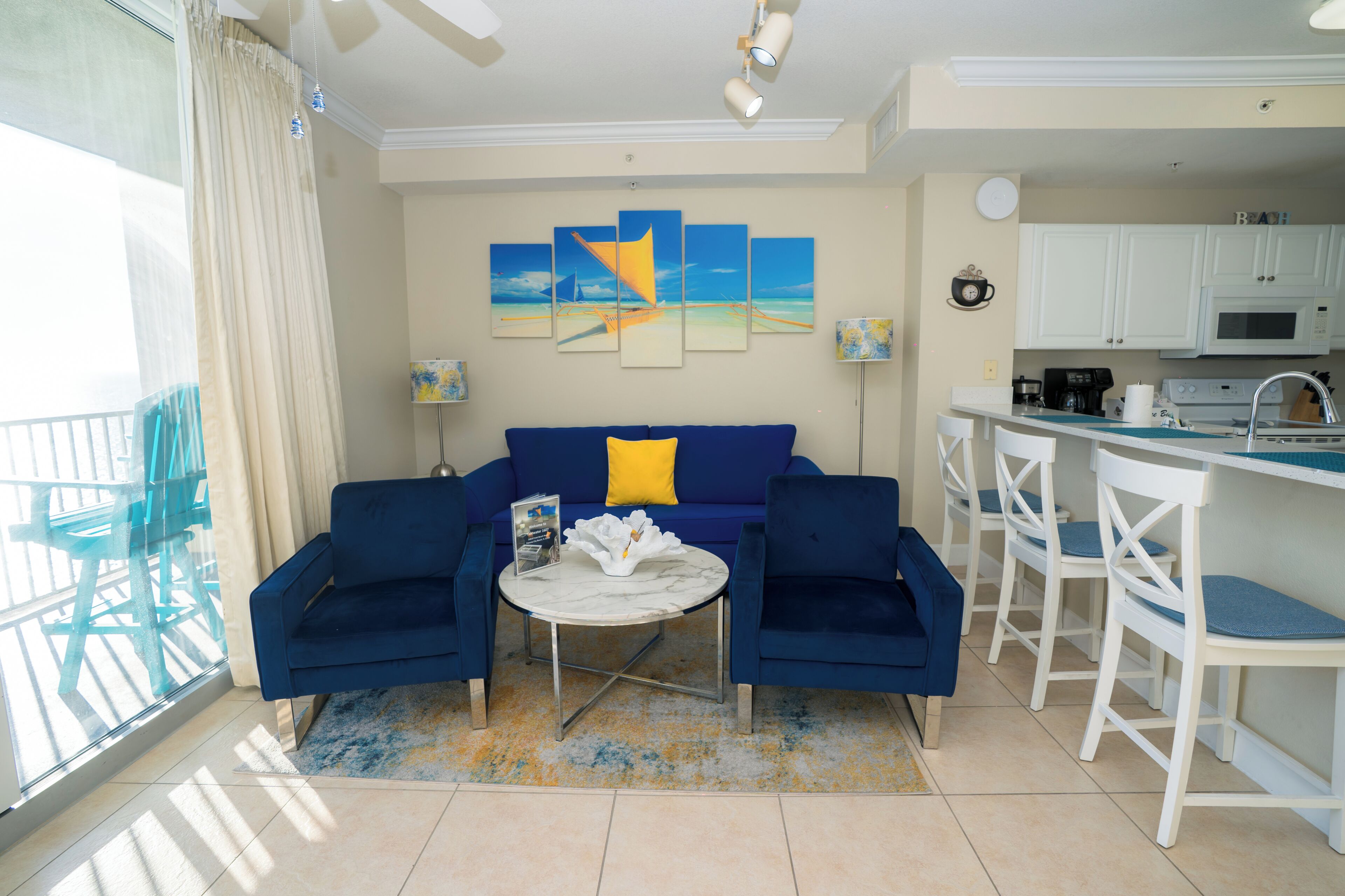 Ein Wohnzimmer mit einem blauen Sofa, einem Couchtisch und Blick zur Küche.