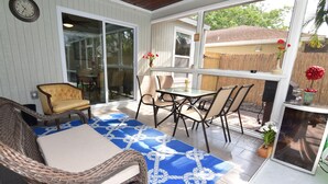 Ein überdachter Patio-Bereich mit Korbmöbeln, einem Tisch und Stühlen.