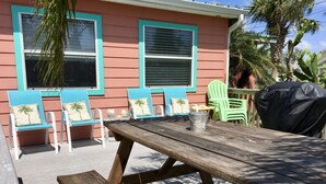 Una terraza de madera con una mesa de picnic, sillas y una parrilla.