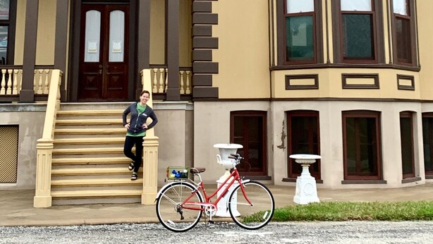 Un edificio grande e histórico con una entrada destacada, una escalera que conduce a la puerta principal y una bicicleta estacionada adelante.