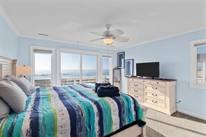Quarto com cama, penteadeira, ventoinha no teto e televisão.