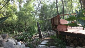 A wooden deck with a stone pathway leading through a garden with large rocks and greenery. - RIVERFRONT Lush&Lux AIRSTREAM Cabin Stunning Views (Three Rivers)