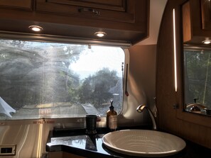 A kitchen with a sink, a window, and a bottle of hand soap. - RIVERFRONT Lush&Lux AIRSTREAM Cabin Stunning Views (Three Rivers)