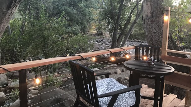 An outdoor seating area with a wooden bench and chairs, surrounded by trees and a rocky landscape. - RIVERFRONT Lush&Lux AIRSTREAM Cabin Stunning Views (Three Rivers)