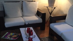 A cozy living room with a sofa, a coffee table with decorative items, a lamp, and a framed picture on the wall. - Bed and breakfast Bugambilias  (Puerto Vallarta)