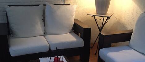 A cozy living room with a sofa, a coffee table with decorative items, a lamp, and a framed picture on the wall.