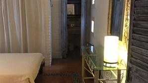A hotel room with a bed, a dresser with a mirror, a lamp, and a door leading to a hallway. - Bed and breakfast Bugambilias  (Puerto Vallarta)