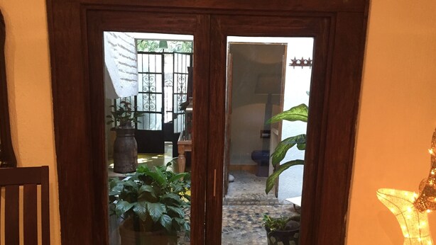 A wooden door with a glass panel, leading to a courtyard with potted plants and a tiled floor. - Bed and breakfast Bugambilias  (Puerto Vallarta)