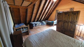Un dormitorio estilo ático con cama nido, una cama individual y un armario.