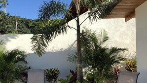 An outdoor seating area with two lounge chairs, a small table, and various plants. - NICE 3 BEDROOM MODERN HOUSE WITH POOL (Sámara)