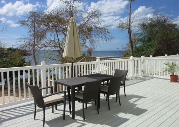 A deck with a table and chairs, a white railing, and a view of the ocean. - Private Luxury Beachfront/Oceanfront Townhome in Beautiful Negril, Jamaica (Negril)