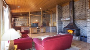 A cozy living room with red sofas, a TV, and a fireplace.