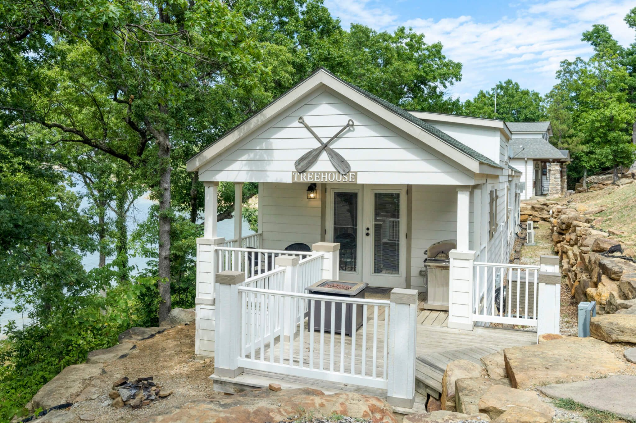 A treehouse with a wooden deck, a small porch, and a sign reading "TREEHOUSE".