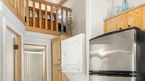 Une cuisine dotée d’un réfrigérateur en acier inoxydable, de meubles de rangement en bois et d’un plafond en bois.