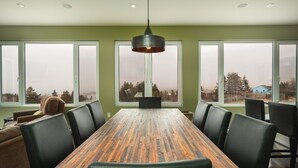 Comedor con una mesa de madera larga, sillas negras y una lámpara colgante.