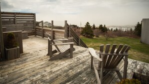 Una terraza de madera con sillas Adirondack, una mesita y una planta en maceta.