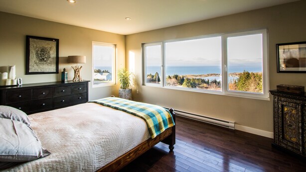 Un dormitorio con una cama grande, un aparador y vistas al exterior.
