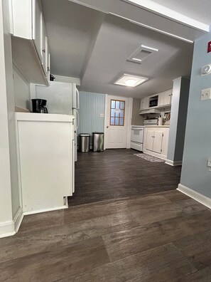 A kitchen with white cabinets, a stainless steel refrigerator, a microwave, and a coffee maker.