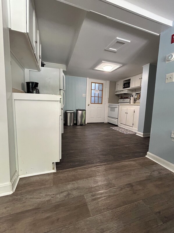 A kitchen with white cabinets, a stainless steel refrigerator, a microwave, and a coffee maker.
