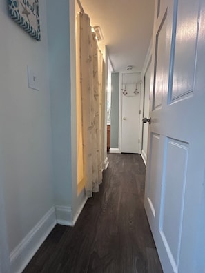 A hallway with a wooden floor, white doors, and a light switch on the wall.